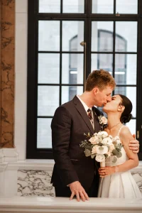 Newlyweds standing at the top of the iconic marble staircase in Camden Town Hall captured by london editorial wedding photographer