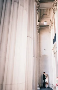 Editorial wedding portrait of an affectionate couple outside Old Marylebone Town Hall underneath columns.